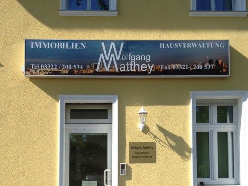 Firmenschild Wolfgang Matthey Immobilien Hausverwaltung an der gelben Fassade